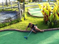 trapped in a tumble  Ben playing mini-golf for the first time yesterday. We hadn't given him a club before because he would use it as a weapon on Sam instead of playing. He was so funny marching around with his club, hitting the ball at random, picking it up, carrying it to the hole, yelling. Ben does everything in LARGE style. He struts. In this shot he tipped over into the rough in his exuberance while taking a shot and couldn't get back up! Mom and I were real peanut gallery watchers - walking behind and cracking up at him while Dave was working with Sam, and trying to teach Ben a few tricks.